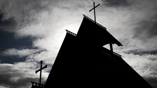 The silhouette of a church with several crosses against a cloudy sky, backdrop Kristin