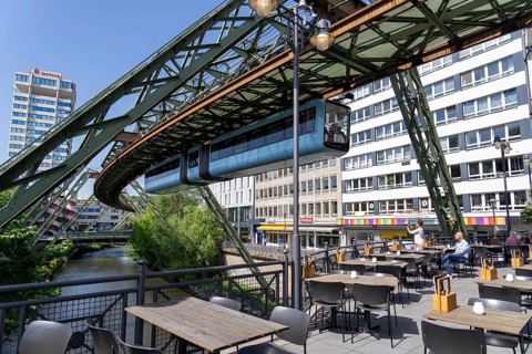 Train of the Wuppertal suspension railway runs along the Wupper, at the main station stop, terrace