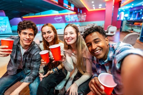 Group of cheerful young multiethnic friends taking a selfie while drinking and having fun in a