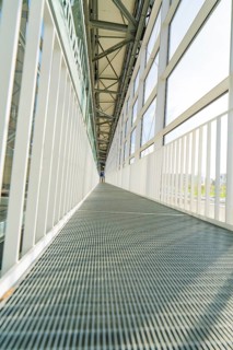 Symmetrical corridor with metal floor and large glass windows, Motorworld Böblingen, Germany,