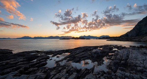 Clouds reflected in a small pond on a rocky coast, coastal landscape at sunset, Henningsvær,