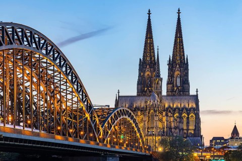 Cologne Cathedral, illuminated in the evening. Hohenzollern Bridge, railway bridge over the Rhine.