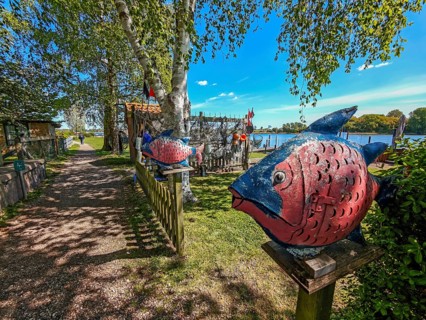 View of the Schlei Fjord from the beach path, art, colourful fish, fishing nets, wooden fence,