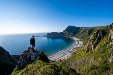Mountaineer with view of coastal landscape, cliffs with summit Måtind or Måtinden, Høyvika beach