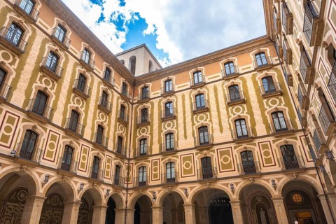 Low angle view of the courtyard of montserrat monastery, showing arched walls, balconies, and