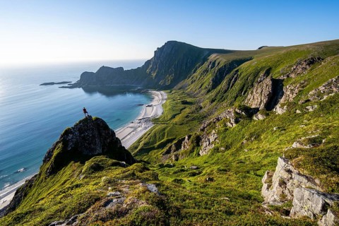 Climber on a rock, view of picturesque coastal landscape, steep coast with peak Måtind or Måtinden,