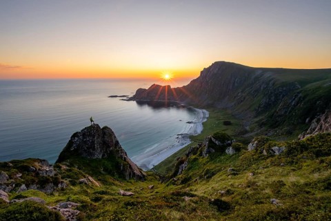 Climber on rocks in front of picturesque landscape, view of coastal landscape at sunset, cliffs and