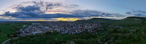 Urban panorama at dusk with dense clouds and rolling hills in the distance, Korb-Steinreinach, Rems