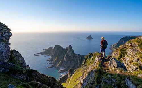 Mountaineer on the summit of Måtind or Måtinden, view of picturesque coastal landscape, rocky coast