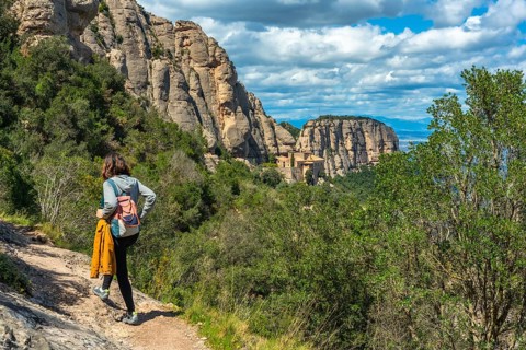 Female tourist walking on a hiking trail in montserrat mountains near barcelona with the santa