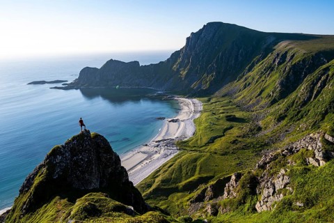 Climber on a rock, view of picturesque coastal landscape, steep coast with peak Måtind or Måtinden,