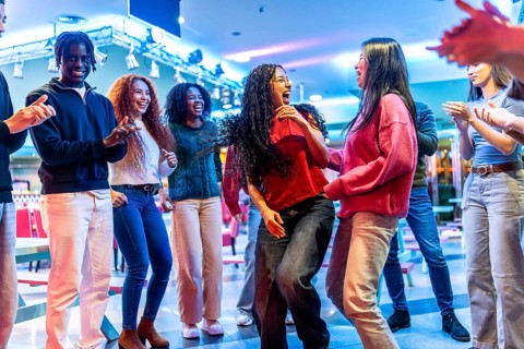 Young multiethnic friends are dancing and having fun together at a bowling alley, enjoying the
