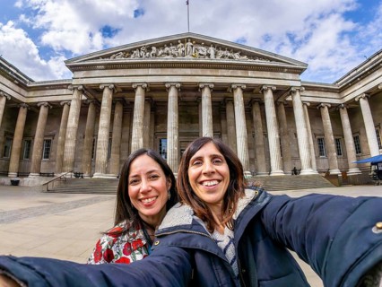 Two happy female tourists are taking a selfie with a fisheye lens in front of the british museum in