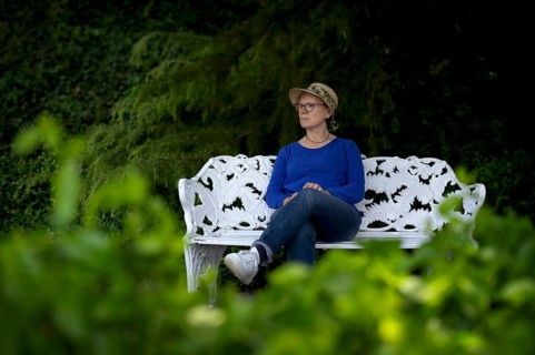 Elderly woman, wearing a sun hat, sitting on a white park bench, pensive, Mainau Island, Constance