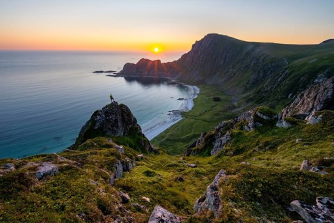 Climber on rocks in front of picturesque landscape, view of coastal landscape at sunset, cliffs and