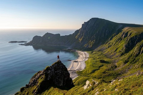Climber on a rock, view of picturesque coastal landscape, steep coast with peak Måtind or Måtinden,