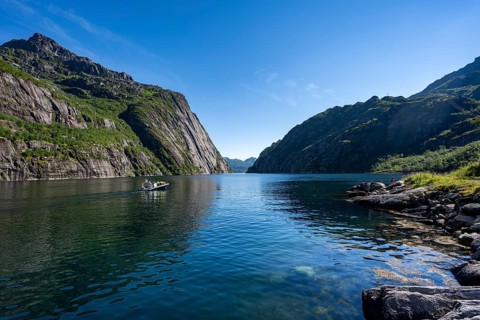 Motorboat with tourists in the fjord Trollfjord, mountains reflected in the water, fjord landscape