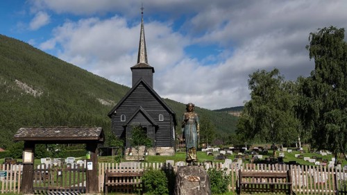 Wooden church in Sel with a cemetery and a statue of Kristian Lavranstochter, the main character