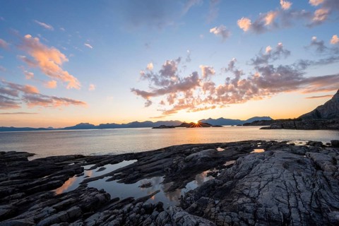 Clouds reflected in a small pond on a rocky coast, coastal landscape at sunset, Henningsvær,
