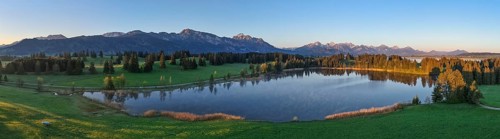 Panoramic view of a lake with mountains and forests at dawn, Hergratsrieder See, Alps, near Füssen,