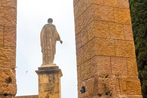 Ancient roman statue standing tall amidst the ruins of tarragona, showcasing the city's rich