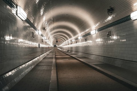 Symmetrically illuminated tiled tunnel with curved lines and depth, old Elbe tunnel, Hamburg,