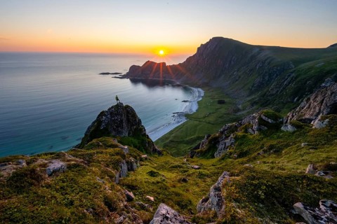 Climber on rocks in front of picturesque landscape, view of coastal landscape at sunset, cliffs and