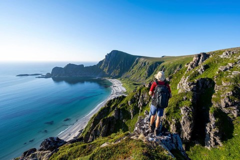 Mountaineer in front of view of coastal landscape, steep coast with summit Måtind or Måtinden,