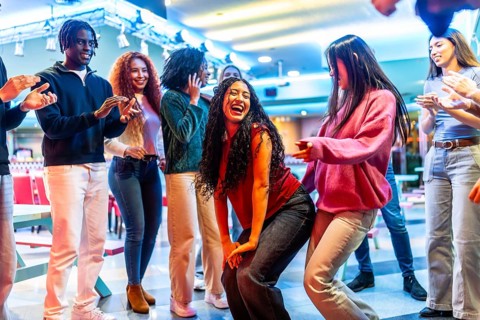 Young diverse friends dancing and having fun at a bowling alley, enjoying their weekend together