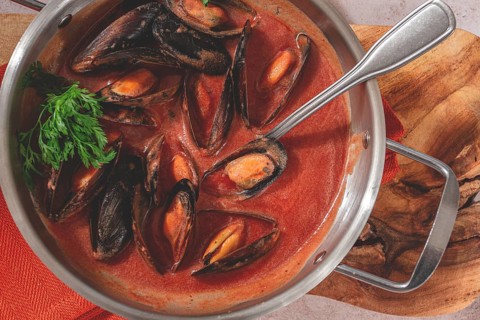 Mussels in tomato sauce, in a silver dish, on a wooden board, rustic style, no people, top view
