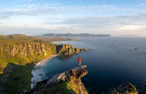 Evening mood, mountaineer standing on a rocky outcrop on the summit of Måtind, view of coastal