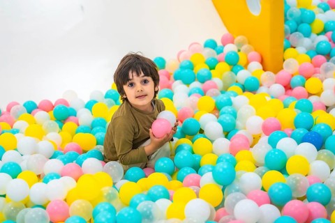 Young boy enjoying playtime in a vibrant ball pit, surrounded by colorful plastic balls in a lively