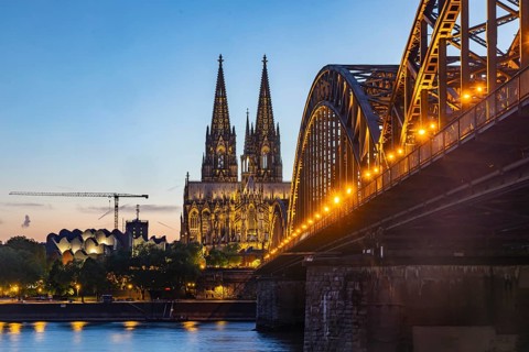 Cologne Cathedral, illuminated in the evening. Hohenzollern Bridge, railway bridge over the Rhine.