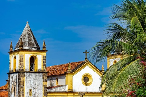 Beautiful baroque church tower amidst the vegetation of the city of Olinda with the sea in the