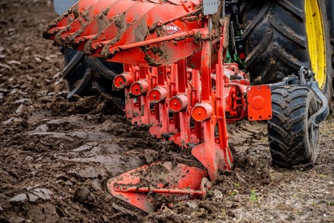 Tractor with a plough preparing the soil of a field for planting, Agriculture, Spring