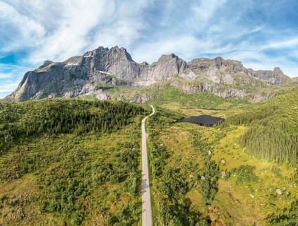 Panoramic aerial view of road in mountain scenery, passing lakes and meadows, road from E10 to