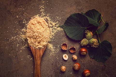 Wooden spoon, with hazelnut flour, on a brown table, top view, no people