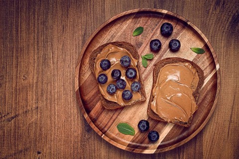 Rye bread with peanut paste and fresh blueberries, top view, no people