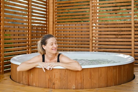 Portrait of carefree happy smiling woman relaxing at outdoor hot tub during her vacation