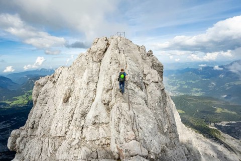 Mountaineer on a narrow rocky ridge on a steel cable, Watzmann crossing to Watzmann Mittelspitze,