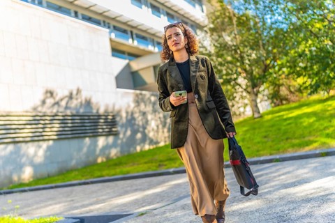 Full length photo of a beauty Arab businesswoman in casual modest clothes walking along the city
