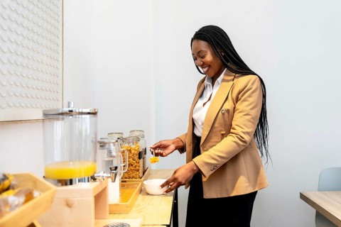 Smiling businesswoman serving breakfast from hotel buffet during business trip, enjoying orange