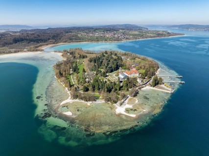 Aerial view of the island of Mainau at low tide with spring-like vegetation, on the horizon the