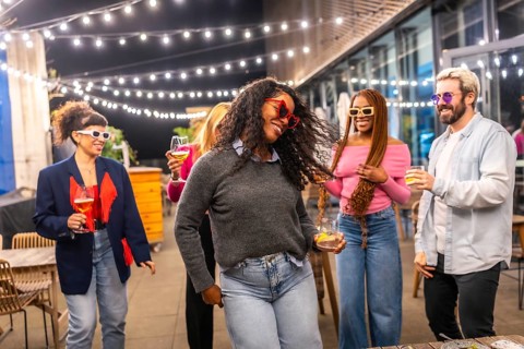 Energetic latina woman dancing with friends at night party in a roof of a bar at city