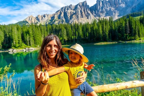 Mother and son smiling and enjoying summer holidays at lake carezza with the latemar mountain range
