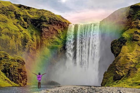 Child in front of Skogar waterfall rainbow Iceland