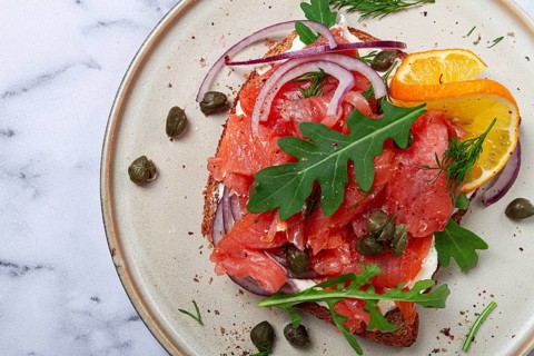 Sandwich with freshly smoked salmon, on black bread, with cottage cheese, with herbs and red