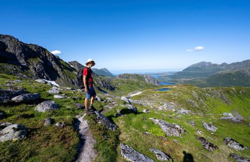 View of mountains and fjord landscape, mountaineer on hiking trail to the summit of Rundfjellet,