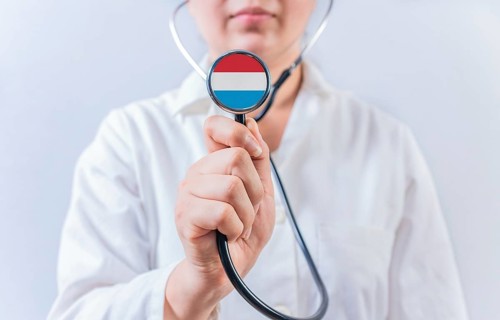 Female doctor holding stethoscope with Luxembourg flag. National health system of Luxembourg