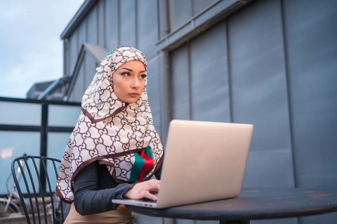 Arab girl with a white veil at the computer on the terrace of a coffe shop, contrabass with the